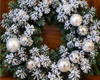 Snowy evergreen Christmas wreath with silver ornaments & snowflakes. Artificially made for you to take home at this week's super sale!