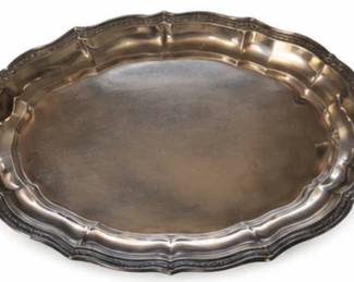 Vintage silver-tone serving tray with ornate handles and scalloped rim.