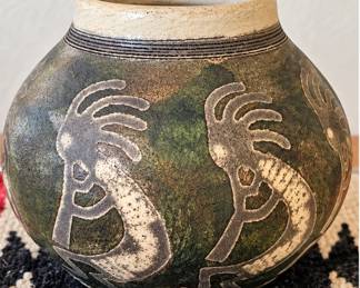 Southwestern pottery vase with Kokopelli-style design and earthy green tones.