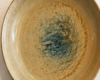 Decorative ceramic bowl with warm tan glaze and abstract blue-brown center design.