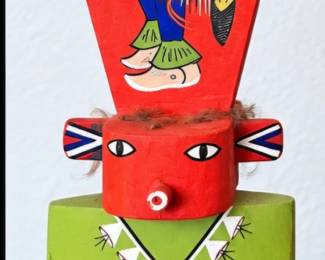 Colorful carved Kachina-style figure with tall red headdress and detailed hand-painted geometric designs.