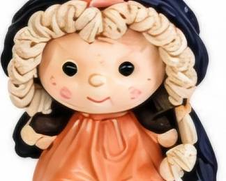 Whimsical girl doll figurine with bonnet and bow.