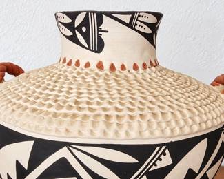 Southwestern pottery vessel with bold black geometric designs, textured detailing and terracotta handles.