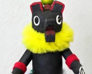 Handcrafted Kachina-style figure with black mask, bright yellow collar, colorful geometric clothing and decorative headpiece.