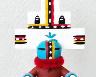 Handcrafted Kachina-style figure with a large geometric headdress, turquoise mask, red collar, painted details and traditional-style garments.