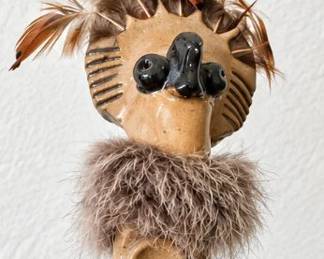 Southwestern ceramic figure with feather accents and Kokopelli-style design.