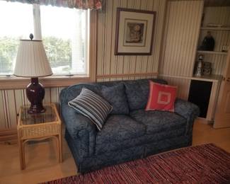 Wicker end table; table lamp; cozy couch; area rug