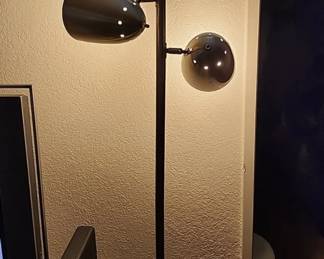 Lamp featuring three adjustable metal cone shades arranged along a tall standing pole.
