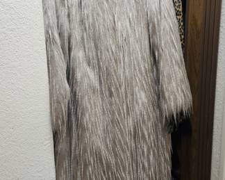 Full-length faux fur coat from the Pamela McCoy Black Diamond Collection. This specific line is highly regarded for its premium, heavy-weight replica furs designed to mimic natural textures like coyote, wolf, or fox. The garment features a long-pile, shaggy finish with multi-tonal gray, cream, and brown striations, giving it a realistic animal-print aesthet