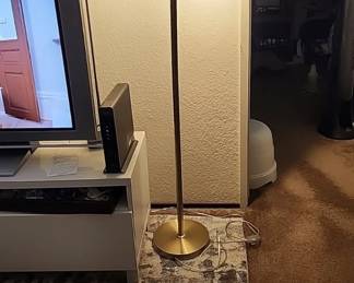Lamp featuring three adjustable metal cone shades arranged along a tall standing pole