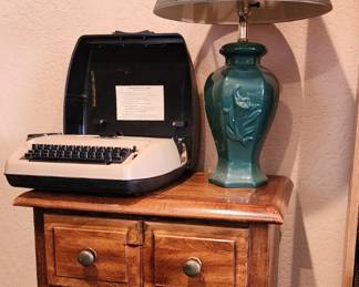 WORKING ELECTRIC TYPEWRITER, LAMP & WOOD NIGHTSTAND – Vintage plug-in electric typewriter in working condition, decorative table lamp with teal ceramic-style base, and wood 3-drawer nightstand/end table.