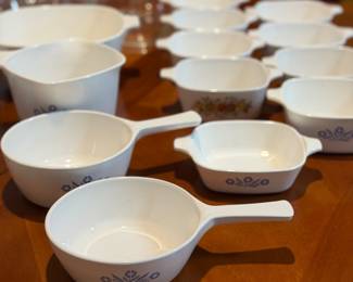 Assorted vintage white CorningWare-style baking and serving dishes, including casseroles, bowls, platters, and divided dishes.