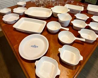 Assorted vintage white CorningWare-style baking and serving dishes, including casseroles, bowls, platters, and divided dishes.