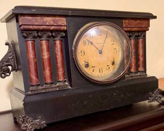 Antique mantel clock with decorative column details and aged finish.