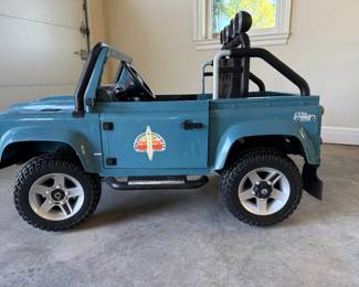 Land Rover Defender child-sized battery powered vehicle - 2 seater. Realistic Land Rover Defender style battery powered in blue with rugged off road styling. Features 2 seats, large treaded wheels, roll bars, side steps, auxilary roof lights