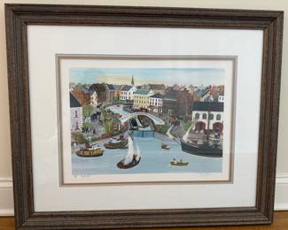 Will Moses Signed & Numbered Limited-Edition Folk Art Print - "York#1". Charming Americana folk-art scene by Will Moses, depicting a bustling historic waterfront town with colorful period buildings, horse-drawn carriages, boats, pedestrians, a canal bridge and church steeple. The detailed composition and whimsical perspective are characteristic of Moses' nostalgic depictions of early American life. The print is hand-signed in pencil by Will Moses and numbered as a limited edition. Presented with layered neutral matting and substantial rustic wood-tone frame. Soft blue, cream and muted earth tones make this an attractive piece for traditional coastal, Americana or country-style interiors.