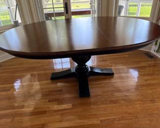 Ethan Allen Cameron Round Dining Table (item 156743): Elegant dining table crafted in USA with a substantial pedestal base and classic transitional styling. Table features a rich wood-finished top contrasted by a dark pedestal base, creating a sophisticated two-tone look. The round table (with extension) expands with leaves to create. a spacious oval dining surface, making it ideal for both everyday dining and large gatherings.