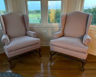 Pair of Classic Traditional Upholstered Wingback Chairs: Elegant pair of traditional wingback chairs featuring high sculpted backs, rolled arms, and graceful Queen Ann-style cabriole legs with carved detailing. Upholstered in a soft blush/taupe fabric with a repeating scallop/fan pattern that gives the chairs a sophisticated updated look.