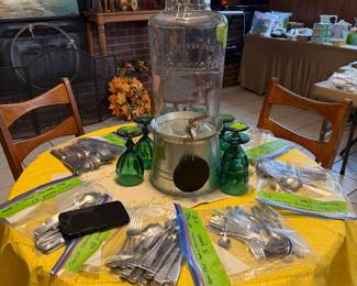 Round card table, flatware and large drink dispenser.