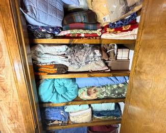 Linen Closet Lot — Blankets, Sheets, and Comforters This linen closet lot includes a full shelf's worth of household bedding: quilted comforters, fleece throw blankets, flat and fitted sheet sets, decorative throws, and pillow covers in assorted colors and patterns. Some items appear to be in original packaging. A practical bulk bedding and linen lot for household use, guest room setup, or donation.
