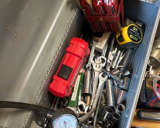 This gray metal toolbox with fold-out cantilever tray is packed with a working assortment of hand tools including combination wrenches, open-end wrenches, deep and shallow sockets, a Stanley FatMax 30-foot tape measure, a tire pressure gauge, and a red drill bit index set. The drop-forged steel wrenches and chrome sockets show honest use but plenty of life remaining. A solid hand tool starter set or shop-restock lot for any home mechanic or DIYer.