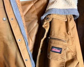 Dickies Insulated Canvas Work Jacket — Size M This Genuine Dickies insulated work jacket in classic tan duck canvas features a quilted nylon lining, a sherpa fleece-lined collar, snap-over-zipper front closure, and zippered chest pocket. The interior tag reads size M/M (38-40). Dickies canvas work jackets are a trusted cold-weather workwear layer for construction, farming, and outdoor trades, and this one shows moderate use with light soiling on the exterior consistent with a working jacket. Sold as found.