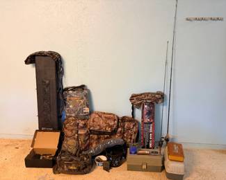 Hunting and Outdoor Gear Lot This hunting and outdoor gear lot includes a hard-sided rifle or shotgun case, a Therm-A-Seat cushion in original camo packaging, multiple Realtree camo bags and packs including a Cabela's branded duffel, a three-man dome tent in camo, two spinning-reel fishing rods, and two tackle boxes with contents. A well-rounded outdoorsman lot covering hunting, fishing, and camping gear in one grouping — ideal for someone gearing up or restocking.