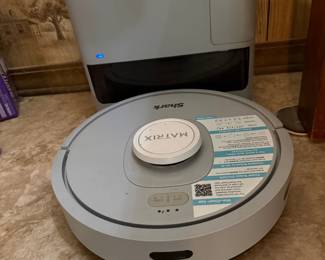 Shark Matrix Robot Vacuum with Self-Emptying Base This Shark Matrix robot vacuum comes with its self-emptying base station in gray and silver. The quick-start instruction sticker appears still attached to the unit, suggesting minimal use or recent setup. Shark Matrix robot vacuums feature smart navigation, self-emptying dustbin capability, and app-based scheduling for hands-free floor cleaning. A strong lot for anyone looking to upgrade to a robotic vacuum system without paying full retail. Working condition not confirmed — sold as found.