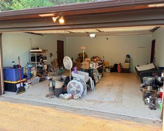 Garage Pickers Lot — Assorted Household and Workshop Items This garage pickers lot covers the remaining miscellaneous items spread across a two-car garage bay — visible contents include oscillating pedestal fans, blue plastic storage totes, assorted small furniture and hardware, and a general assortment of household and workshop odds and ends. Pickers lots give estate sale buyers the chance to browse, dig, and claim individual finds at an open-lot price. Contents are sold as-is, as they sit — come ready to treasure hunt. Item availability and arrangement may vary at pickup.