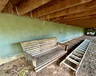 Weathered wooden porch swing and aluminum step ladder