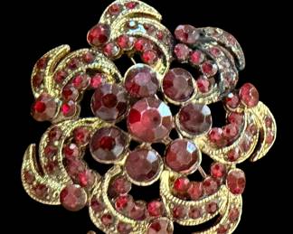 vintage mid-century gold-tone domed cluster brooch featuring deep ruby-red rhinestones in a floral or pinwheel swirl design