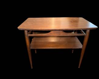 vintage mid-century modern two-tier wooden end table featuring distinctive tapered legs and a decorative cutout rail