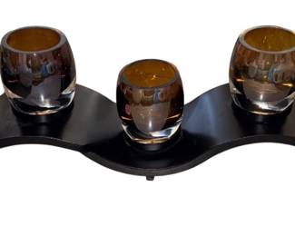 a Mikasa Solaris Wave Votive Centerpiece featuring a curved black metal base and five amber glass votive cups.