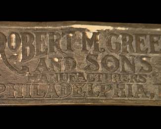 an antique metal maker's or brand plaque from Robert M. Green & Sons, famous manufacturers of soda fountains and drugstore equipment based in Philadelphia, Pennsylvania. Robert M. Green is historically credited with originating or popularizing the "ice cream soda" at the Franklin Institute semi-centennial celebration in Philadelphia in 1874, which helped launch their successful manufacturing business of ornate marble, onyx, and mahogany soda fountains.