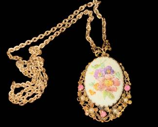a vintage gold-tone filigree pendant necklace featuring a hand-painted floral porcelain or milk glass cabochon