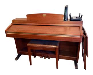 a classic Yamaha Clavinova digital piano, a long-running and highly regarded line of home digital pianos first introduced in 1983. This specific model features an elegant dark wood grain cabinet, an arched integrated music rest with a gold centerpiece badge, three foot pedals, and a sliding key cover (fallboard). It is paired with a matching cushioned Yamaha piano bench
