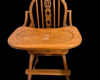 vintage wooden high chair featuring a distinctive carved center splat on its spindle back and a wide wooden tray