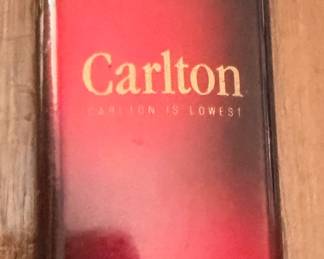 vintage red and gold Carlton Cigarettes refillable butane pocket lighter from the 1980s, featuring the brand's classic "Carlton Is Lowest" advertising text