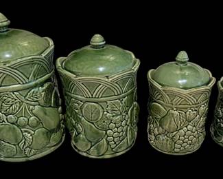 a vintage four-piece green majolica ceramic kitchen canister set featuring an embossed fruit and lattice motif