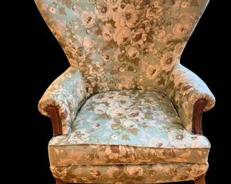This classic armchair features a sweeping high wingback silhouette and soft sage-green floral upholstery reminiscent of mid-20th-century traditional furniture design.