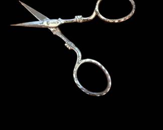 pair of vintage ornate metal embroidery or sewing scissors with engraved floral handles.