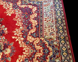 Persian area rug featuring an intricate floral and scrollwork design on a red field
