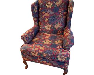This is a traditional floral tapestry wingback armchair featuring rolled arms and dark carved wooden cabriole legs.