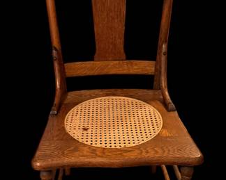 an antique wooden side chair, resembling a turn-of-the-century T-back or splat-back chair with a round cane insert in a solid wood seat