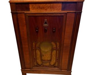 This is a vintage Silvertone floor console tube radio, a brand manufactured by Colonial Radio Corporation and other suppliers specifically for Sears, Roebuck & Co. during the golden age of radio.  This is an Art Deco-era lowboy or standard upright console cabinet crafted with multi-toned wood veneers, featuring a highly-figured burled accent panel along the top face.  1934