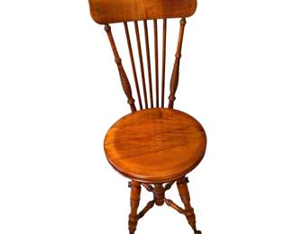 This is a Victorian, piano chair or music chair with a high spindle back, turned wooden legs, and glass ball-and-claw feet.