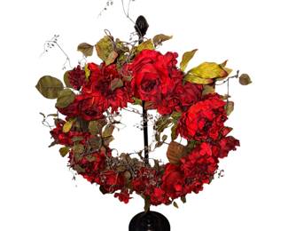 red floral wreath elevated on a central black pedestal stand.