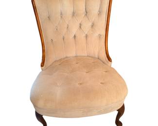 a vintage tufted accent or slipper chair, featuring light beige upholstery, button tufting, and a wooden frame with curved legs