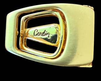 a vintage gold-toned metal belt buckle featuring an engraved "cardin" logo in a nested geometric frame, made in Italy