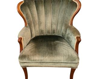 This is  a vintage wood-framed channel-back armchair upholstered in a sage or olive green velvet fabric with exposed carved wooden trim. 